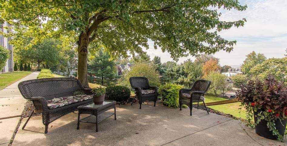 Chairs and tables under the tree in the garden of Rittenhouse Village Senior Living