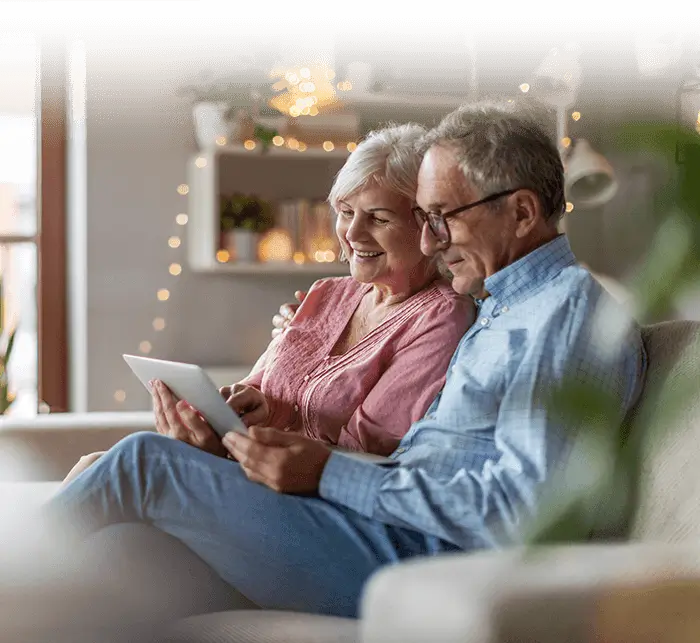 Senior couple sitting on sofa and viewing tablet