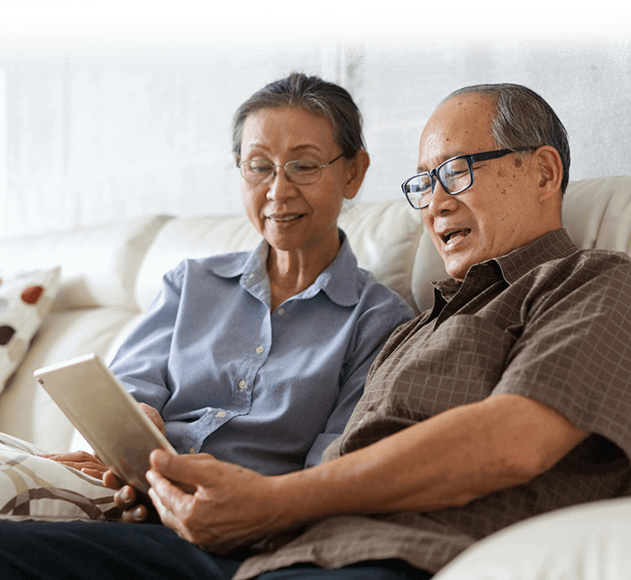 Senior couple sitting in sofa and watching their tablet
